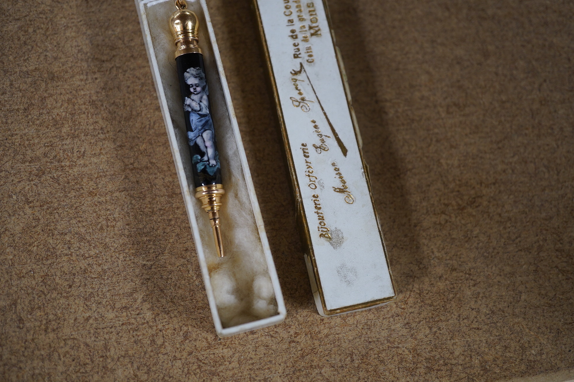 A Continental yellow metal and enamel propelling pencil decorated with putti, 72mm. Condition - poor (slight damage to the enamel).